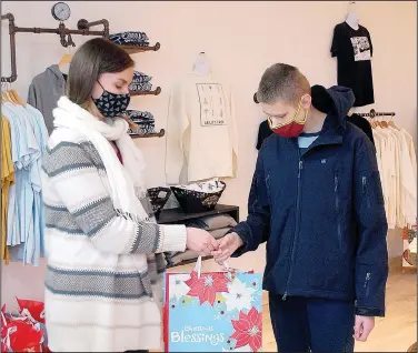  ?? (NWA Democrat-Gazette/Janelle Jessen) ?? Maddy Shultz hands a Christmas goodie bag to Deven Clayberg inside the new Ability Tree Studio and Store last week. Ability Tree gave out bags filled with Christmas activities for members last week.