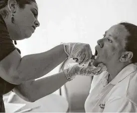  ??  ?? Kat Rodriguez, Intake Specialist for Colibrí Center for Human Rights, swabs the inside of Nohemy Alvares’ cheek to collect a DNA sample in their hotel room in Nogales, Sonora, Mexico.