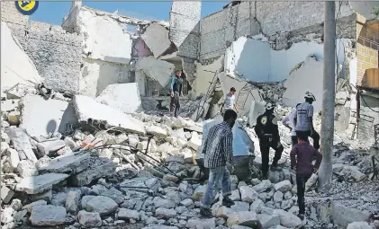  ?? CP PHOTO ?? In this photo provided by the Syrian Civil Defense group known as the White Helmets, members of the Civil Defense group and residents inspect damaged buildings after airstrikes hit the Bustan al-Qasr neighborho­od in Aleppo, Syria, Sunday.