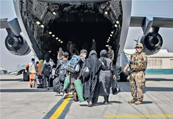  ??  ?? American troops help Afghan families board a plane at Kabul airport as the US starts making its final exit plans