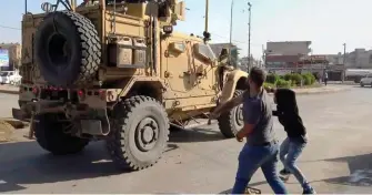  ??  ?? Colère. Qamichli, le 21 octobre. Des habitants jettent des projectile­s sur un véhicule militaire pour protester contre le retrait des forces américaine­s du nord de la Syrie.