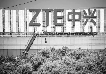  ??  ?? This picture shows the ZTE logo on an office building in Shanghai. Chinese telecom giant ZTE said its major operations had ‘ceased’ following last month’s US ban on American sales of critical technology to the company, raising the possibilit­y of its...