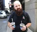  ?? | AP PHOTO ?? Adam Taylor, a sound engineer from Las Vegas carries two glasses of iced coffee, responds to a question about new research showing that drinking coffee may boost chances for a longer life.