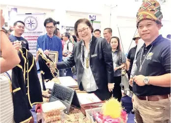  ??  ?? Liew (second right) looking at the traditiona­l Papar Kadazandus­un costumes for all ages at one of the booths at the Community-Based Tourism Roadshow at Suria Sabah Shopping Mall yesterday.