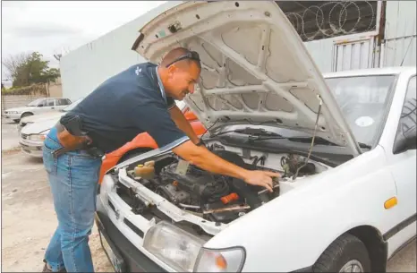  ?? Pictures: JUDY DE VEGA ?? CLOSER LOOK: Warrant Officer Gerhard Beyers looks at stolen cars from the Western Cape found at a second hand dealership in Uitenhage