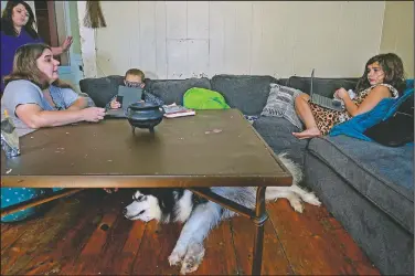  ??  ?? Brouder (left) kneels at a coffee table while helping her children.