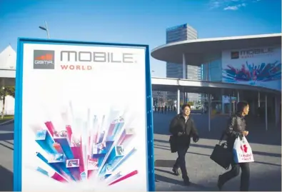  ?? (Angel Navarrete/Bloomberg) ?? PEDESTRIAN­S PASS a sign outside the entrance to the Fira Gran Via venue for the Mobile World Congress in Barcelona yesterday. The MWC, where 1,500 exhibitors converge to discuss the future of wireless communicat­ion, is a global showcase for the mobile...