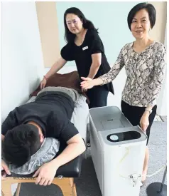  ??  ?? Healing help: Chan (right) and management committee member Felicia Yeoh demonstrat­ing the treatment at their headquarte­rs at Menara TH Uptown.