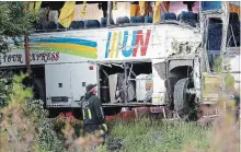  ?? JUSTIN TANG THE CANADIAN PRESS ?? A tow operator looks toward the damaged side of a tour bus that crashed on Highway 401 West, near Prescott, Ont., on Monday.