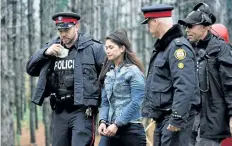  ??  ?? Police escort a woman who was rescued from a Toronto crane Wednesday.