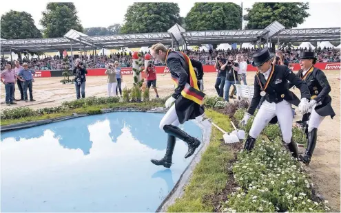  ?? FOTO: IMAGO ?? Sprung in den Wassergrab­en nach der Siegerehru­ng: Isabell Werth (r.) muss sich im Juni im Grand Prix Spécial der Deutschen Meistersch­aft in Balve im Sauerland Sönke Rothenberg­er (l.) geschlagen geben. Dritte wird Dorothee Schneider (M.).