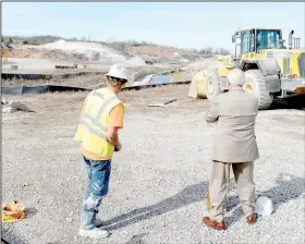  ?? (File Photo/NWA Democrat-Gazette) ?? Zack Brisco, blaster with Explosive Contractor­s Inc., watches a now-flattened hillside collapse with Mayor Peter Christie, who just pushed a plunger to detonate a series of charges that turned part of the hill into a pile of dirt and rocks nearly a year ago in January.