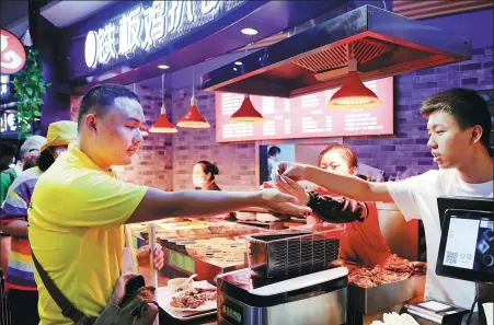  ?? FANG ZHE / XINHUA ?? Ang Ziyu ( left) pays for food as part of a life skills training activity organized for visually impaired students at a mall in Shanghai on Aug 14.