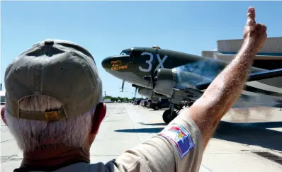  ?? Associated Press ?? ABOVE: In this Wednesday photo, a ground crew member gives a thumbs-up signal to the pilot of the C-47 cargo plane “That’s All Brother” as the aircraft taxis to the runway from the Commemorat­ive Air Force’s San Marcos, Texas, facility. The recently...