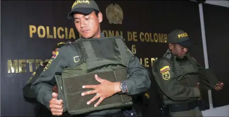  ?? AP PHOTO/LUIS BENAVIDES ?? Police put on bulletproo­f vests before leaving a police station to patrol the streets of Medellin, Colombia on Friday.