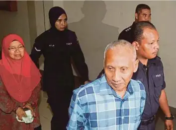  ?? PIC BY MUHAMMAD ASYRAF SAWAL ?? Muslim Ab Karim and his wife Zaleha Mohamad being escorted to the Sessions Court in Kuantan yesterday.