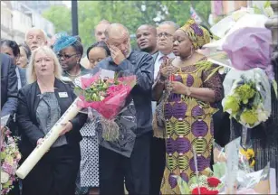  ?? AP PHOTO ?? George Psaradakis (centre), the driver of the number 30 bus which was blown up in Tavistock Square July 7, 2005, looks at floral tributes left close to the scene of the bombings in London Tuesday as Britons marked the 10th anniversar­y of the suicide...