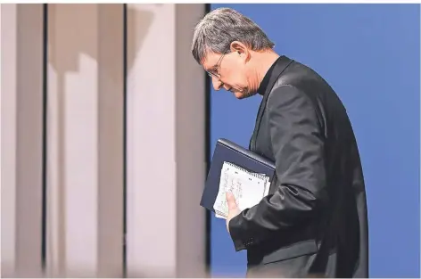  ?? FOTO: INA FASSBENDER/DPA ?? Rainer Maria Kardinal Woelki nach der Pressekonf­erenz am Donnerstag. Das Missbrauch­sgutachten trägt er unter dem Arm.