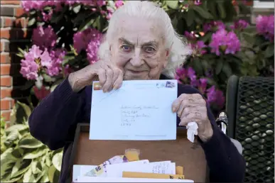  ?? CHARLES KRUPA — THE ASSOCIATED PRESS ?? Flo Young, 93, originally from Cambridge, Mass., holds up a pen pal letter outside the Sullivan County Health Care nursing home on June 8in Unity, N.H. In a letter-writing effort during the virus pandemic to connect nursing home residents in two neighborin­g communitie­s, residents now are receiving pen pal letters from across the United States.