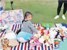  ?? ?? A girl displays some of her dolls in a community flea market in Sanlin of the Pudong New Area. — Ti Gong