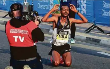  ?? Atiq-ur-Rehman/Gulf News ?? Tamirat Tola from Ethiopia celebrates after winning the men’s race of the Standard Chartered Dubai Marathon with a time of 2:04:11 yesterday.