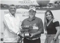  ??  ?? El señor Rafael Villalona, presidente de la Fedogolf, entrega la copa de campeón al señor Kim Bidgood, ganador del evento, figura Laura Hernández, presidenta de la empresa Primma Valores.