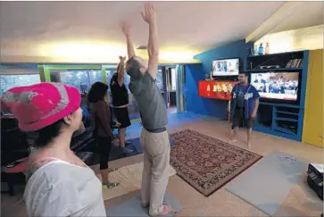  ?? Mark Boster Los Angeles Times ?? KELLY PERINE, a Los Feliz resident, leads a group of friends through yoga in his living room as they watch former FBI Director James B. Comey’s testimony on television­s tuned to MSNBC and Fox News.