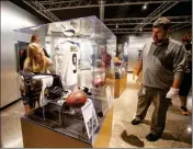  ?? ASSOCIATED PRESS ?? IN THIS OCT. 9, 2018, file photo, Pro Football Hall of Fame curator Jason Aikens, right, watches Rachel Knapp as they work on a display in Canton, Ohio, of memorabili­a of New Orleans Saints quarterbac­k Drew Brees from his record-setting game against the Washington Redskins.