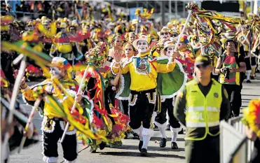  ?? CéSAR BOLíVAR Y JESúS RICO ?? Un agente de la Policía custodia el desfile de la Gran Parada, mientras un grupo de Garabato baila.