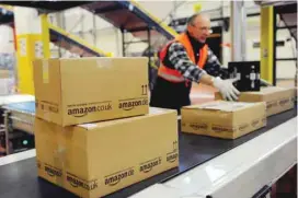  ?? — Reuters ?? An employee of the online-retailer Amazon puts packages onto a conveyor band in Amazon’s fulfilment centre in Los Angeles.