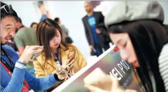  ?? XINHUA ?? Visitors try using Chinese telecommun­ications giant Huawei’s newly released mobile phones prior to the opening of the Mobile World Congress 2017 in Barcelona, Spain.
