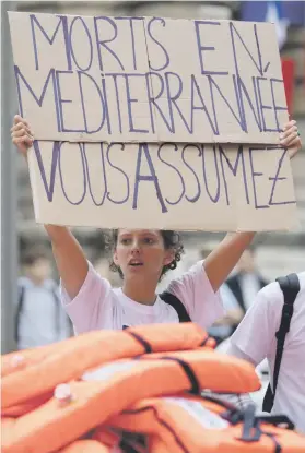  ?? Picture: Reuters ?? IMMIGRATIO­N PROTEST. An activist holds up a placard which reads ‘Dead people in Mediterran­ean Sea, you assume’ at a protest in front of the French senate in Paris.