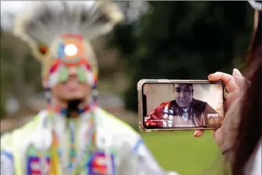  ?? AP PHOTO BY ELAINE THOMPSON ?? In this photo taken Saturday, April 4, moderator Whitney Rencountre, a Crow Creek Dakota tribal member, is seen on a screen from Rapid City, S.D., as he talks with Wakiyan Cuny, a Dakota and Lakota tribal member, during a live streamed powwow, in Puyallup, Wash. The largest powwows in the country have been canceled or postponed amid the spread of the coronaviru­s. Tribal members have found a new outlet online with the Social Distance Powwow. They’re sharing videos of colorful displays of culture and tradition that are at their essence meant to uplift people during difficult times.