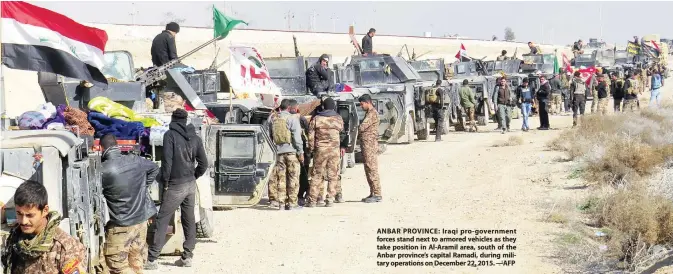  ??  ?? ANBAR PROVINCE: Iraqi pro-government forces stand next to armored vehicles as they take position in Al-Aramil area, south of the Anbar province’s capital Ramadi, during military operations on December 22, 2015. —AFP