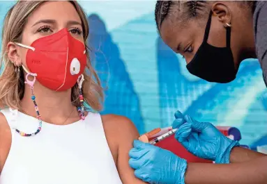  ?? THOMAS HAWTHORNE/THE REPUBLIC ?? Maria Jose, left, receives a COVID-19 vaccinatio­n at a pop-up site in a parking lot next to Antigone Books in Tucson on May 20.