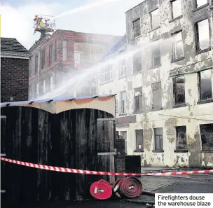  ??  ?? Firefighte­rs douse the warehouse blaze