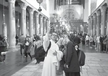  ?? ABBAS MOMANI/GETTY-AFP ?? Christian worshipper­s pose for a selfie Saturday at the Church of the Nativity during Christmas celebratio­ns in Bethlehem in the Israeli-occupied West Bank.