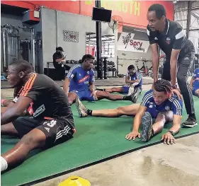  ?? RACHID PARCHMENT ?? Jermie Lynch (sitting right) going through stretches with his Portmore teammates.