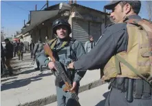  ?? — AFP ?? A distraught man is carried following explosions at a Shia cultural centre in Kabul on Thursday. ( Right) Afghan policemen stand guard after explosions, which were claimed by the ISIS militant group.