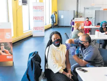  ?? JOSE M. OSORIO/CHICAGO TRIBUNE ?? Jada Johnson receives the first dose of the Moderna COVID-19 vaccine from Armando Ambriz, medical assistant with Esperanza Health Centers, at the Gage Park Vaccinatio­n Site in Chicago on Feb. 19.