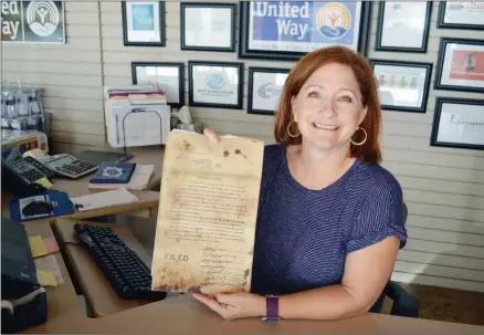  ?? TAMMY KEITH/RIVER VALLEY & OZARK EDITION ?? Maret Cahill-Wicks, executive director of the United Way of Central Arkansas, holds a copy of the 1957 document that formed the Faulkner Community Fund. Fifteen men and women from Faulkner County cities signed the document and formed the first board, which became the United Way agency. A 60thbirthd­ay celebratio­n for the organizati­on will take place from 2-6 p.m. Saturday at the University of Central Arkansas practice field before the football game.