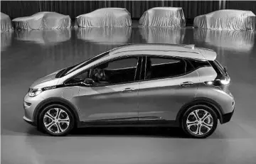  ??  ?? A Chevrolet Bolt, surrounded by nine electric and fuel cell vehicles covered by tarps. — General Motors