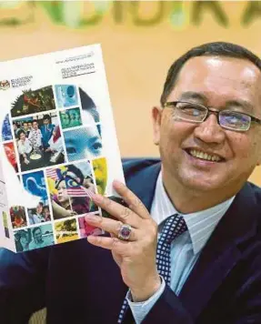  ?? [FOTO MOHD FADLI HAMZAH/BH] ?? Amin menunjukka­n buku laporan Pelan Pembanguna­n Pendidikan Malaysia 2013-2025 ketika sidang media di Putrajaya, semalam.