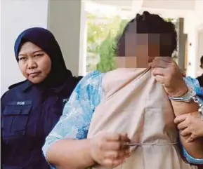  ?? PIC BY RAMDZAN MASIAM ?? A police officer escorting the 60-year-old woman to the Bukit Mertajam magistrate’s court yesterday.