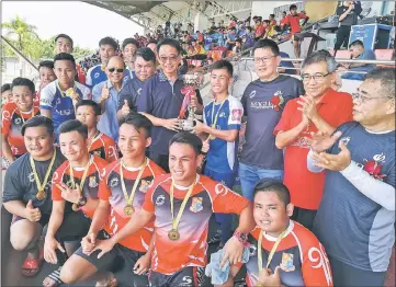  ??  ?? File photo shows Tourism, Arts, Culture, Youth and Sports Minister Datuk Abdul Karim Hamzah (centre) presenting the trophy to the team captain from SMK Sacred Heart after winning the Boys’ U-18 category of the Bro Albinus Challenge Cup. Looking on are Jeffery Ting (right), Dato Sri Barthomole­w Wong (third right) and Song (seventh right).