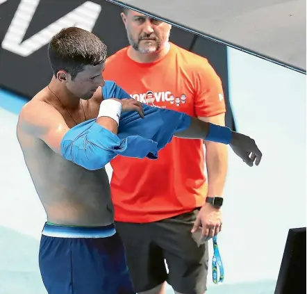  ?? AP ?? Defending champion Novak Djokovic changes his shirt during a practice session at Rod Laver Arena on Tuesday.