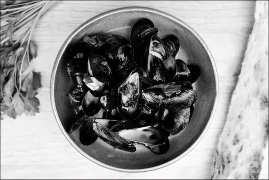  ?? KARSTEN MORAN / THE NEW YORK TIMES ?? Don’t be alarmed by the lack of salt in our recipe for steamed mussels with garlic and parsley. When the mussels yawn open, they release their briny liquid into the pot, seasoning the wine in the process.