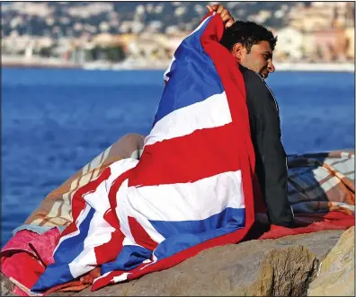  ??  ?? Heading here? A migrant – draped in a Union flag sleeping bag – sits at the French-Italian border