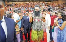  ??  ?? Saint Dr Gurmeet Ram Rahim Singh Ji Insan, center, greets followers as he arrives for a press conference ahead of the release of his new movie ‘MSG, The Warrior Lion Heart.’