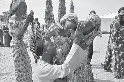  ?? AP Photo/Olamikan Gbemiga ?? Family members offer celebrator­y prayers Saturday as they greet a relative, one of the released kidnapped Nigeria schoolgirl­s, in Abuja, Nigeria. The 82 Nigerian schoolgirl­s, who were recently released after more than three years in Boko Haram...